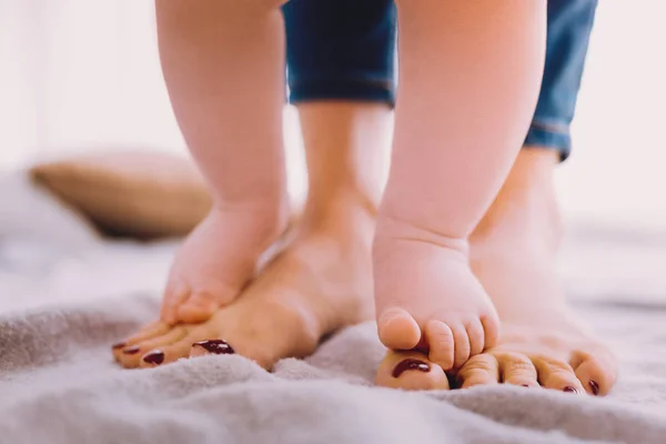 Carino bambino in piedi sui piedi di una madre e trovare l'equilibrio — Foto Stock