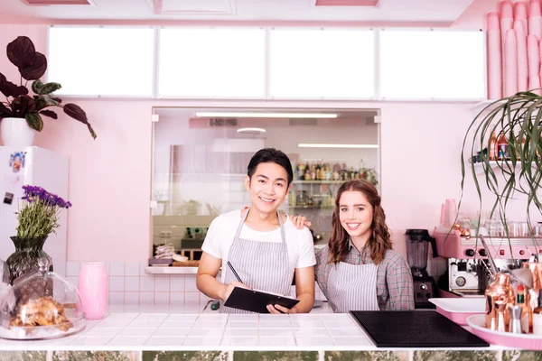 Двоє молодих усміхнених офіціантів готуються до робочого дня — стокове фото