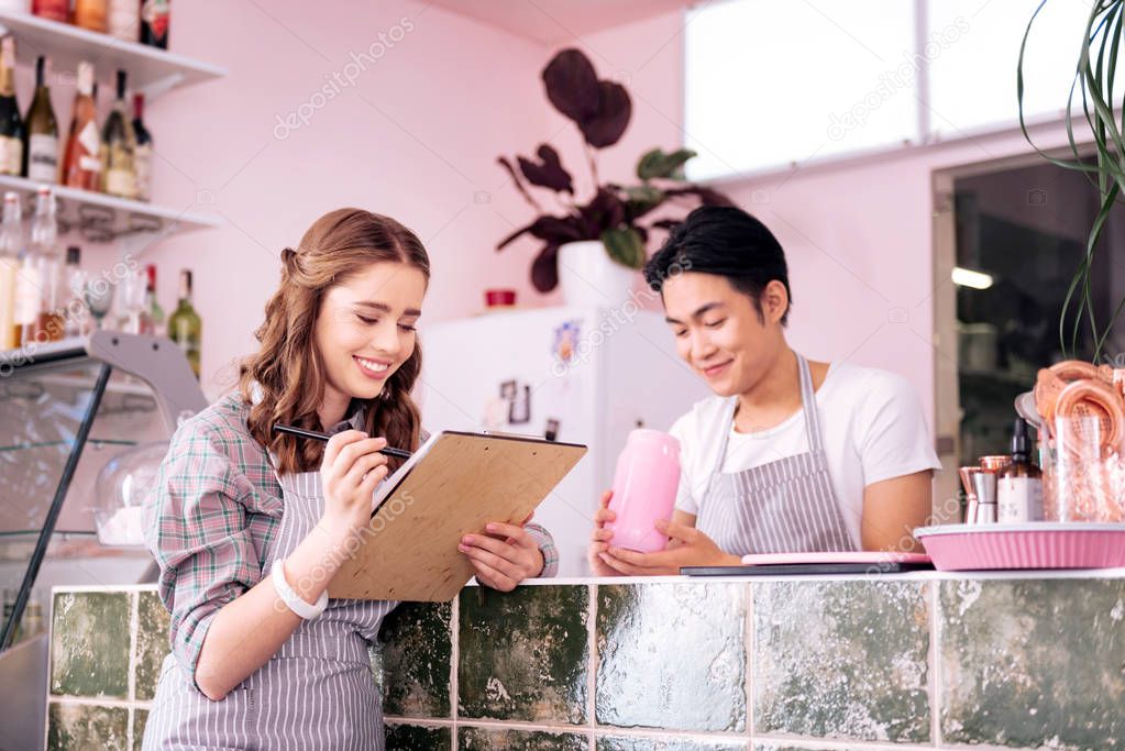 Blonde-haired waiter assistant reading summer menu