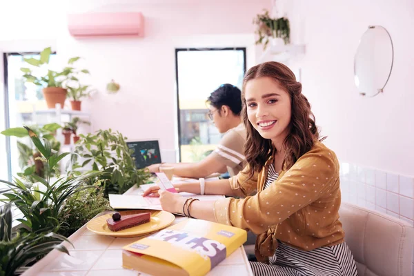 Beaming student wearing striped dress eating cheesecake — Stock Photo, Image