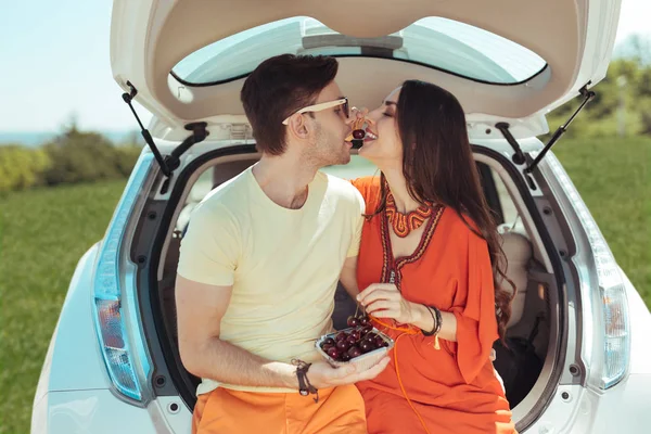 Bonito casal amoroso comer cereja doce fora de seu carro juntos — Fotografia de Stock