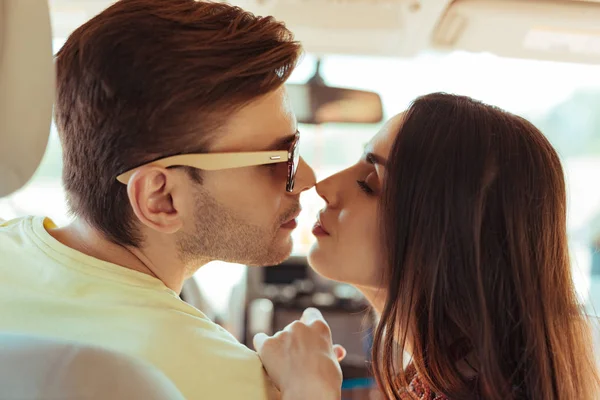 Темноволоса людина в сонцезахисних окулярах цілує свою дружину — стокове фото