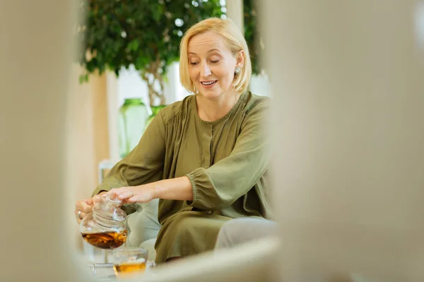 Восхитительная пожилая женщина наливает чай — стоковое фото