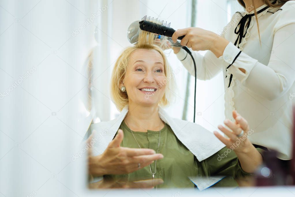 Pleasant skillful woman holding a hairdryer