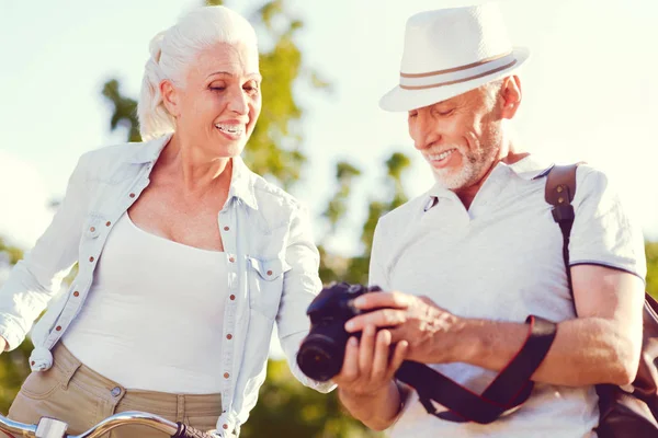 Radiante pareja mayor sonriendo mientras mira aunque fotos — Foto de Stock