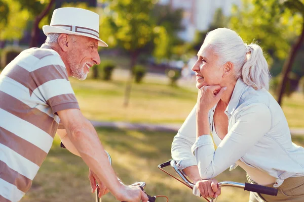 Loving senior couple chatting after bicycling in park