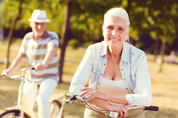 Positif esprit dame âgée souriant tout en s'appuyant sur le vélo — Photo