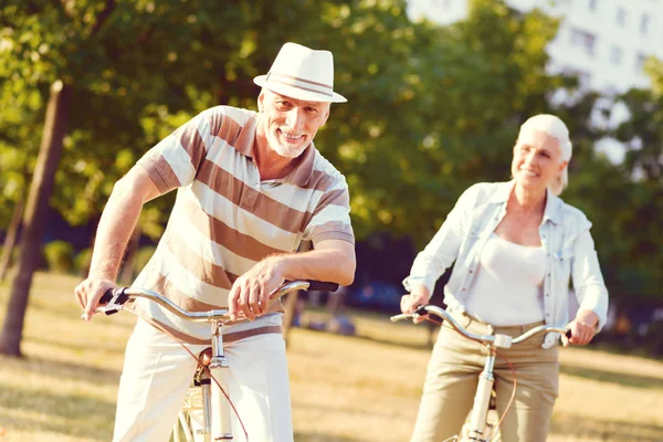 Красивый зрелый джентльмен улыбается после езды на велосипеде со своей женой — стоковое фото