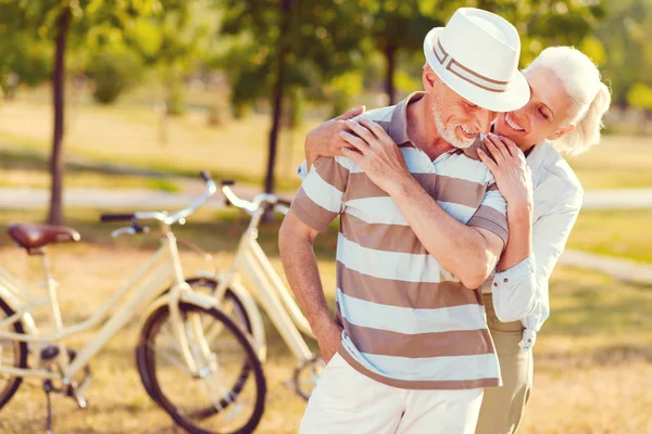 Kärleksfull äldre man och hustru omfamnar och ler — Stockfoto