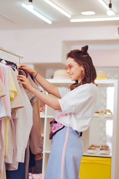 Real shopaholic sonriendo mientras encuentra nueva chaqueta blanca — Foto de Stock