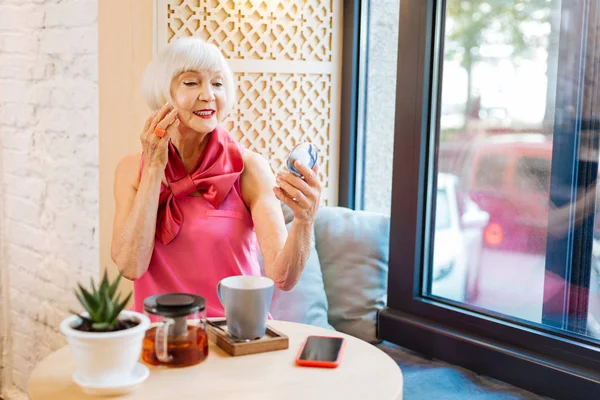 Mulher idosa positiva olhando para o seu reflexo — Fotografia de Stock
