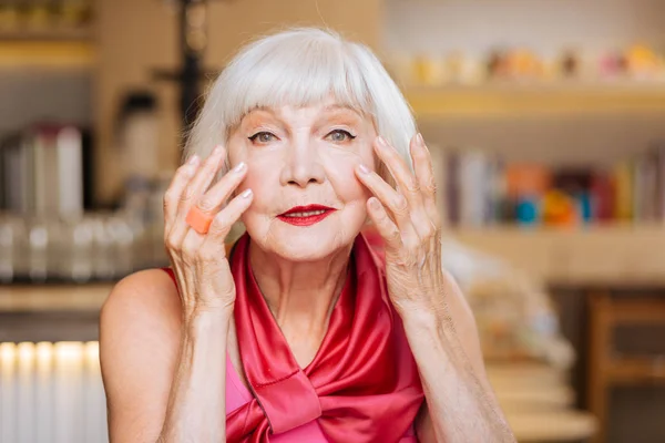 Gioiosa donna anziana che si tocca il viso — Foto Stock