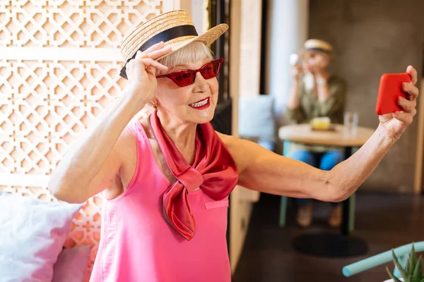 Позитивная пожилая женщина чинит солнечные очки — стоковое фото