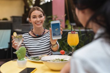 Kadın gösteren hava tahmini telefonunda gülümseyen
