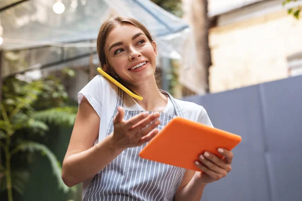 Serveuse brune vérifiant la réservation de table tout en parlant au téléphone — Photo