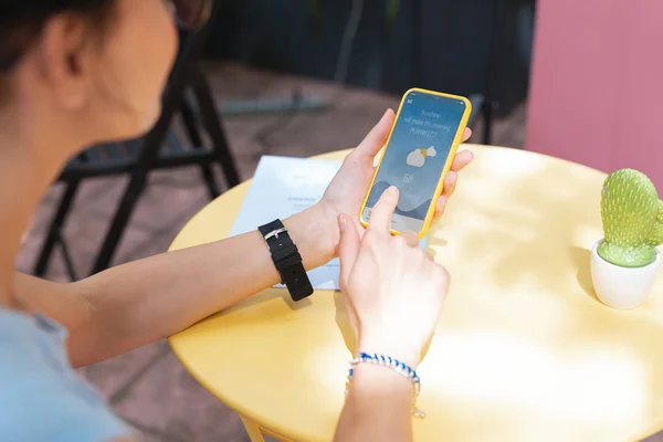 Moderna trabajadora remota revisando pronóstico del tiempo en su teléfono —  Fotos de Stock