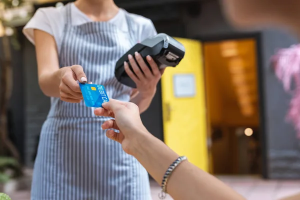 Stijlvolle vrouw dragen van leuke armband betalen voor koffie door kaart — Stockfoto