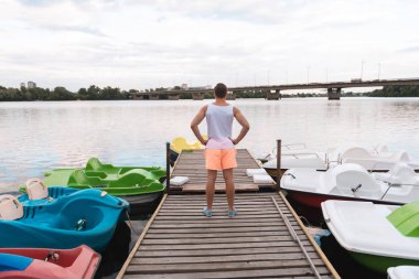 Kas beyaz gömlek ve nehir kenarında duran turuncu şort giyen adam
