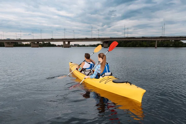 Liebespaar paddelt gemeinsam unter der Brücke — Stockfoto