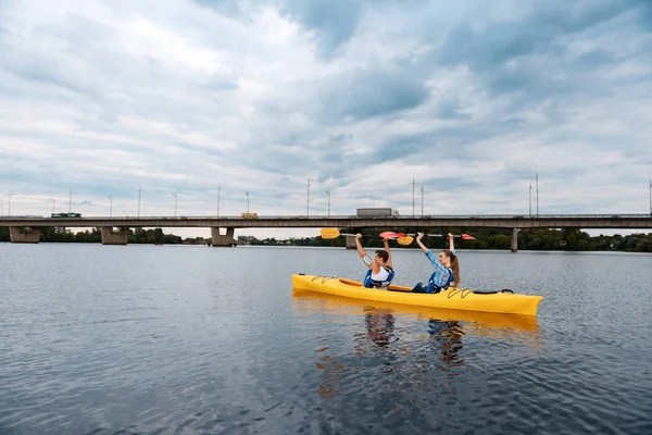 Активные спортсмены гребут на каноэ, поднимая свои весла — стоковое фото