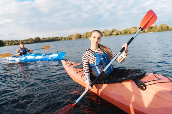 Gut aussehende Frau mit gestreiftem Hemd und Schwimmweste im Kajak — Stockfoto