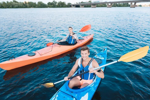 Gut aussehender Sportler mit Schwimmweste sitzt im Kanu — Stockfoto