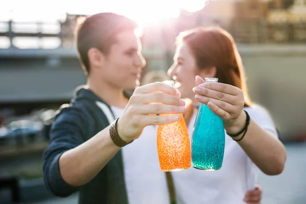 Botellas con bebidas en manos de jóvenes alegres —  Fotos de Stock