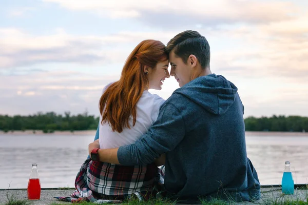 Alegre feliz pareja sentado cerca del río — Foto de Stock