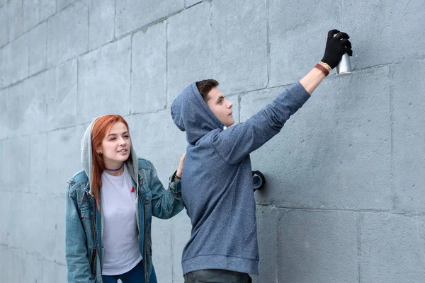 Pleasant young couple drawing graffiti on the wall — Stock Photo, Image