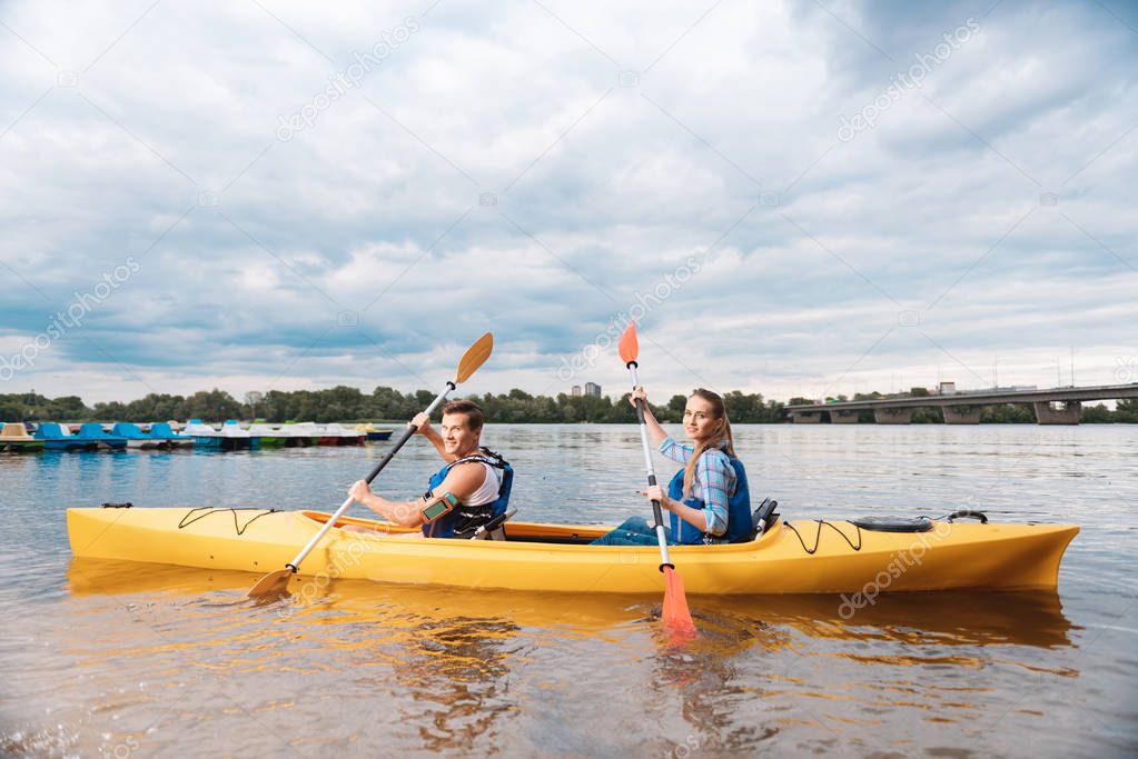 Active tourists rowing with paddles sitting in canoe