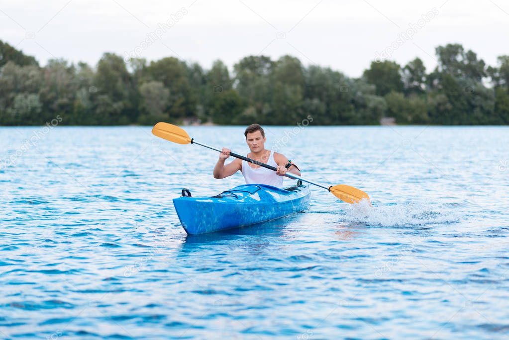 Strong muscle man holding paddles while rowing in canoe