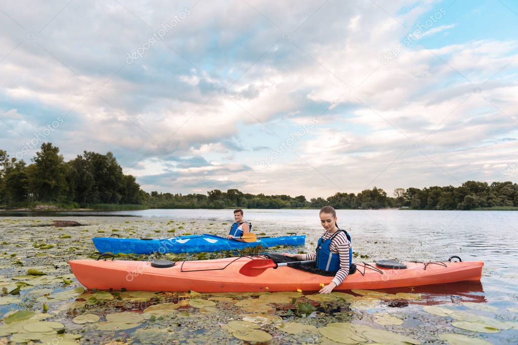 Loving couple enjoying beautiful landscape while rowing in canoe