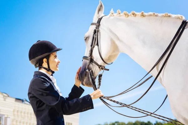 Jinete femenino con casco negro mirando a caballo blanco — Foto de Stock