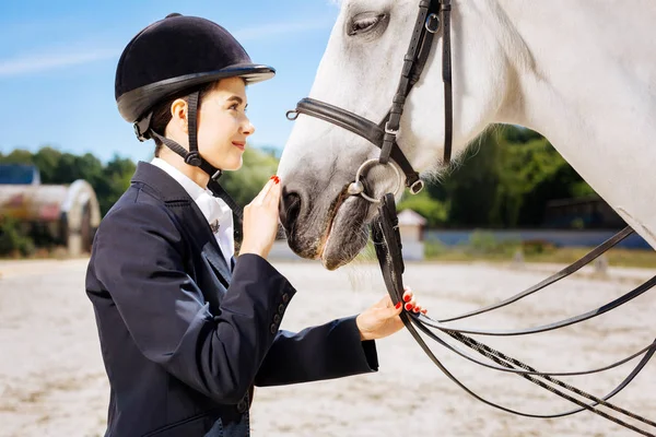 Atractivo jinete mirando a los ojos de su caballo blanco — Foto de Stock