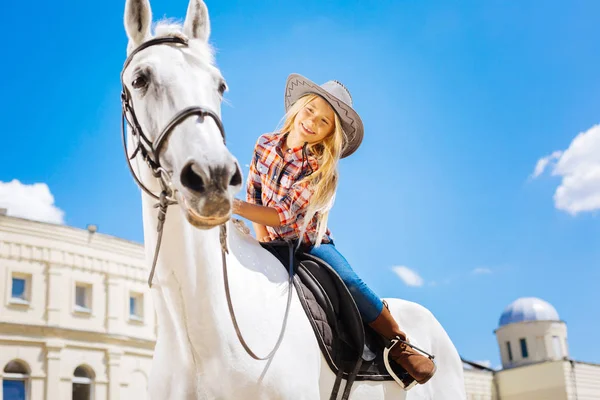 Beaming schoolgirl touching her white racing horse — Stock Photo, Image