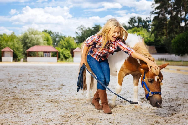 Laughing girl having much fun with little cute pony with braid — Stock Photo, Image