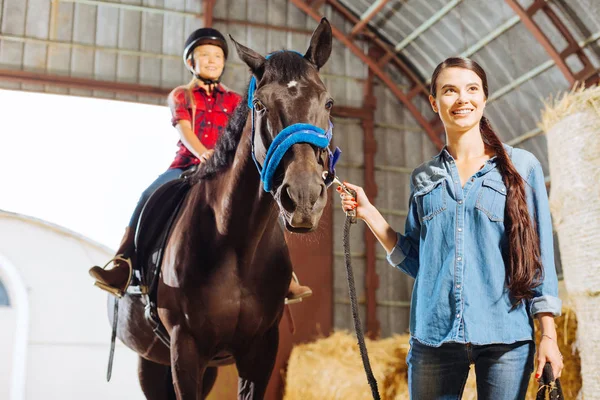 Riding teacher leading horse with blonde-haired beaming girl — Stock Photo, Image