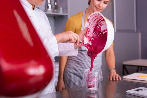 Chef pouring mousse for macaroons into measuring cup — Stock Photo, Image