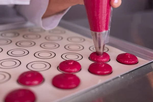 Koch formt kleine rosa Makronen auf Backpapier — Stockfoto