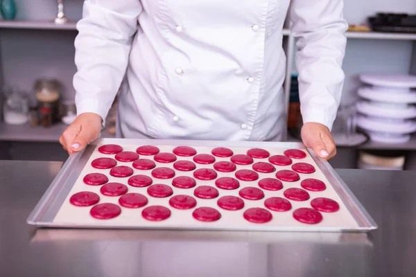 Chef femelle tenant une plaque à pâtisserie avec des biscuits colorés — Photo