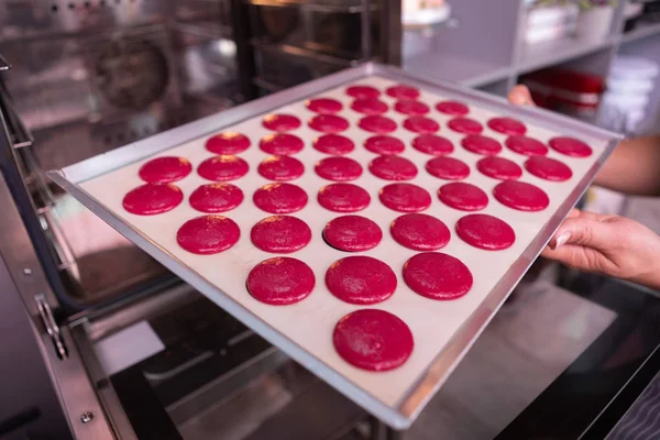 Boulanger professionnel mettant plaque à pâtisserie avec macarons roses — Photo