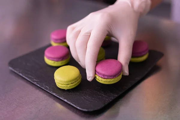 Master of confectionary putting nice macaroons on black plate