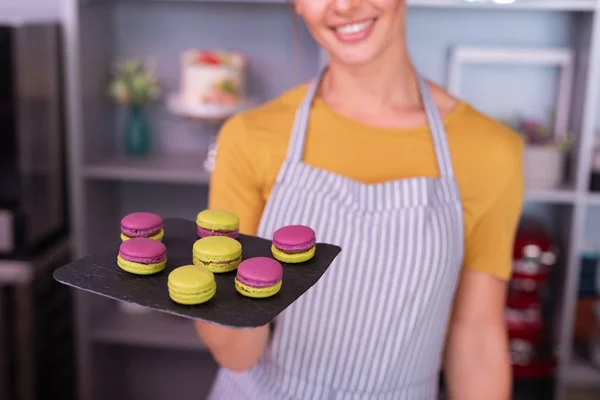 Joven panadero sonriendo ampliamente después de cocinar macarrones brillantes —  Fotos de Stock