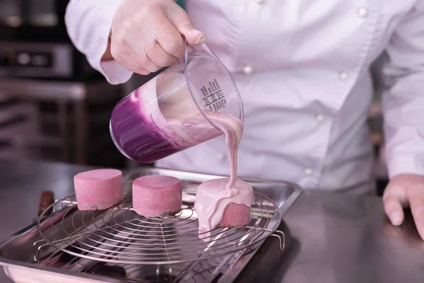 Confiseur professionnel mettant glaçage miroir sur des gâteaux aux myrtilles — Photo