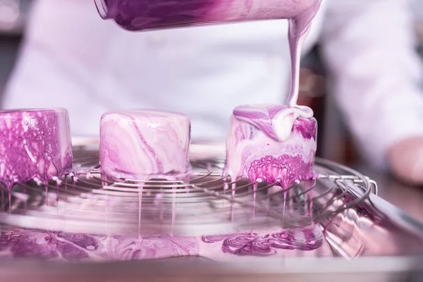 Chef versant glaçage miroir blanc et violet sur des gâteaux — Photo