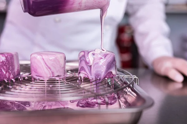 Professeur d'école de cuisine montrant des gâteaux de cuisine avec glaçage miroir — Photo