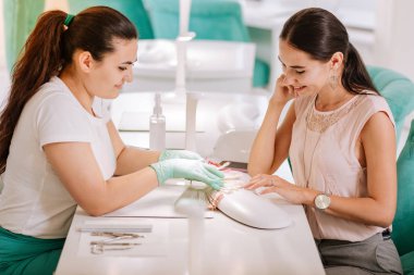 Güzel oje renkleri müvekkili sunan deneyimli çivi sanatçı