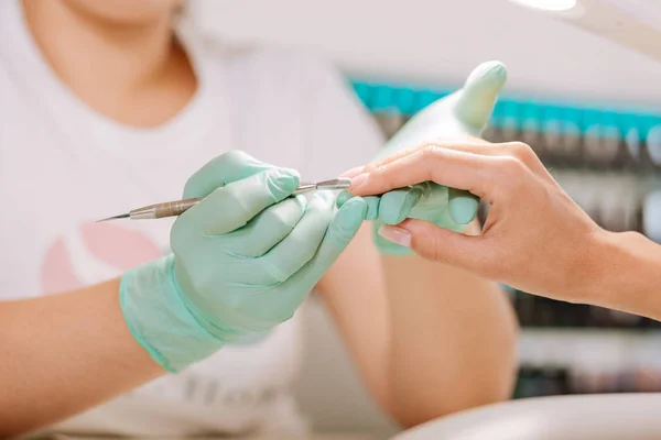 Maestro de uñas utilizando la herramienta de manicura para eliminar la cutícula —  Fotos de Stock