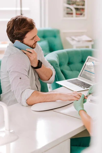 Busy businessman talking on the phone working on laptop in nail bar