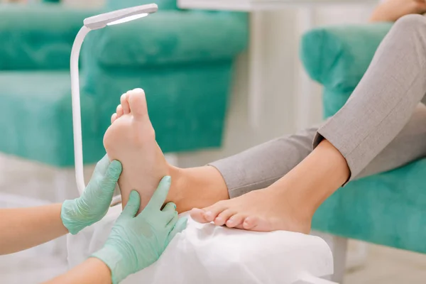 Опытный педикюр, делающий массаж ног для женщины — стоковое фото